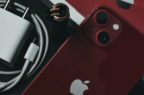 Product red iPhone 13 besides charger and Apple box