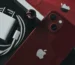 Product red iPhone 13 besides charger and Apple box